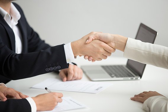 Candidate and employer shaking hands across an interview desk